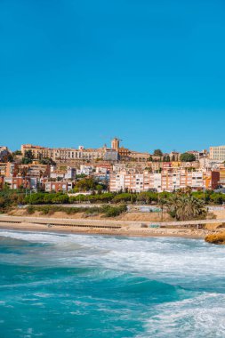 Tarragona, İspanya - 23 Ekim 2025: Tarragona 'daki Playa del Miracle kıyı manzarası, kıyıda dalgalar kırılıyor ve arka planda Alta tarihi bölgesi görülüyor