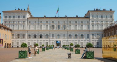 Torino, İtalya - 20 Haziran 2025: Neoklasik cephesi ve Musei Reali kompleksinin girişinin üzerindeki İtalyan bayrağı ile Palazzo Reale, yeşil bitkilerle kaplı bir geçide bakıyor.