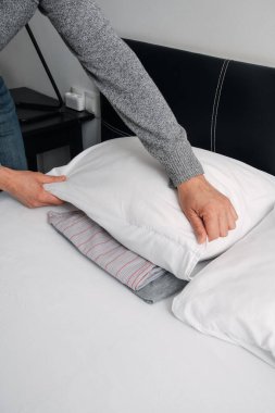 İspanya 'da yaygın bir gece alışkanlığını takip eden ve İtalya' da da pratik yapan bir adamın katlanmış pijamalarını yeni yapılmış bir yatağın altına koymak için iki eliyle yastığı kaldırışı.