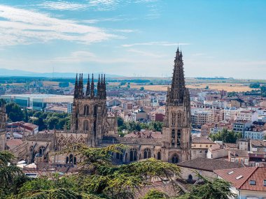 İspanya 'daki Burgos Katedrali' nin Gotik kuleleri şehir çatıları, uzak tepeler ve aydınlık yaz atmosferiyle çevrili tarihi merkezin üzerinde yükselir.