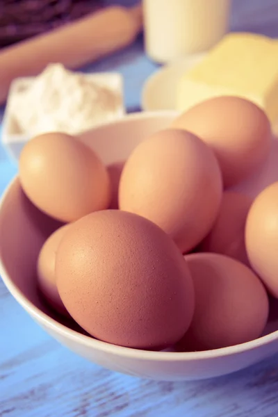 Huevos, mantequilla, harina y leche sobre una mesa de madera azul — Foto de Stock