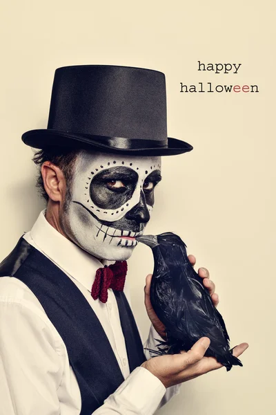 Hombre con maquillaje calaveras y cuervo, y texto feliz halloween — Foto de Stock