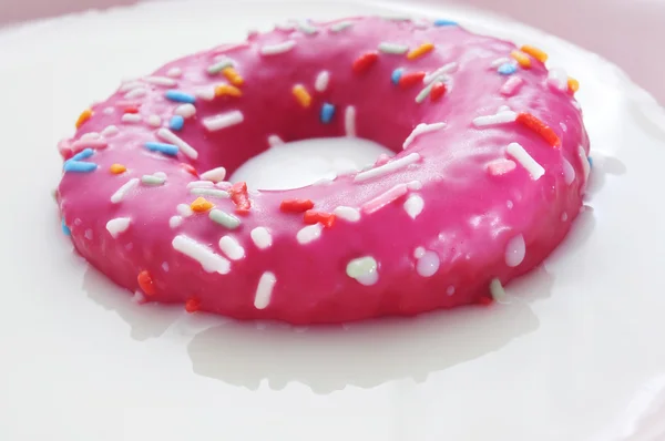 Donut rosa sendo embebido em leite — Fotografia de Stock