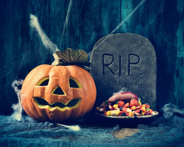 Carved pumpkin, gravestone and Halloween candies — Stock Photo, Image