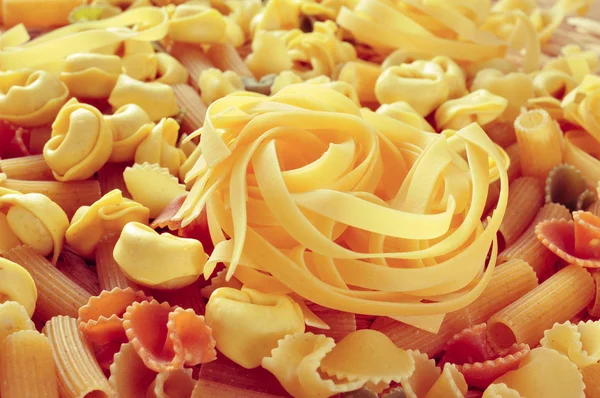 Uncooked pasta, such as tortellini, tagliatelle or penne rigate — Stock Photo, Image