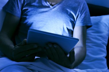 genç adam geceleri yatakta tablet kullanma