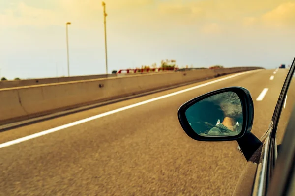 Młody człowiek jazda samochodem odbite w lustrze skrzydła — Zdjęcie stockowe