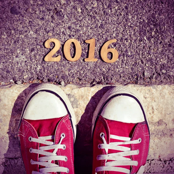 Man feet and wooden numbers forming the number 2016 — Stock Photo, Image