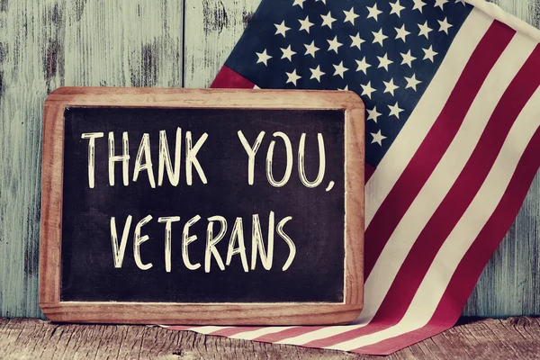 Текст благодарности ветеранам на доске и флаге США — стоковое фото