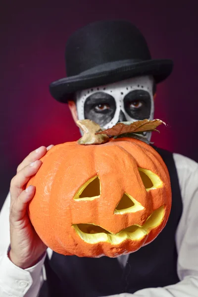 Hombre con maquillaje calaveras mexicanas y calabaza tallada —  Fotos de Stock