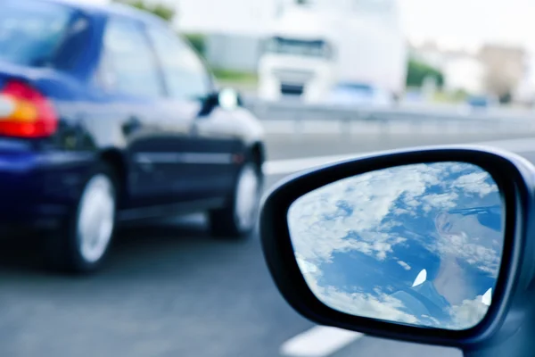 Jovem dirigindo um carro refletido no espelho da asa — Fotografia de Stock