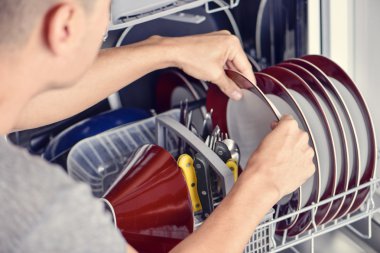 young man putting a dishwashing machine clipart