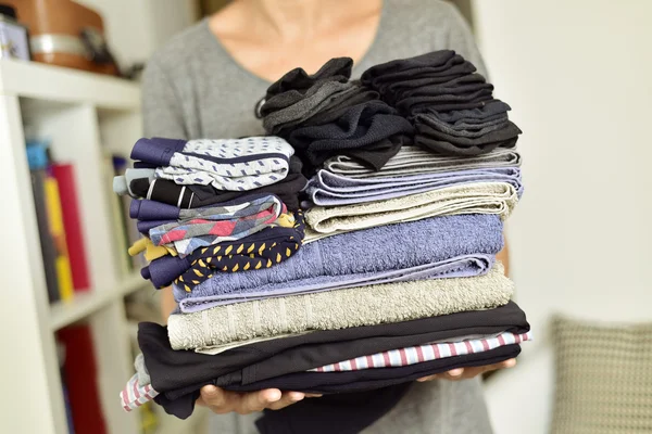 Jeune homme avec une pile de vêtements pliés — Photo