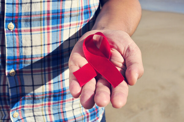 young man with a red ribbon for the fight against AIDS, filtered