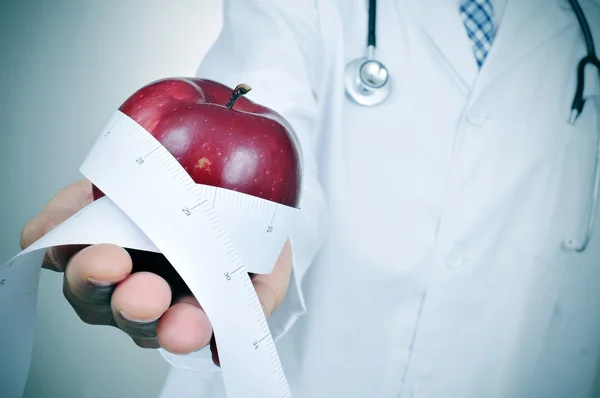 Doctor man with a red apple and a measuring tape — Stock Photo, Image