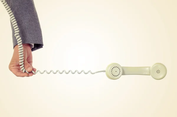 Young man holds the cord of a telephone — Stock Photo, Image