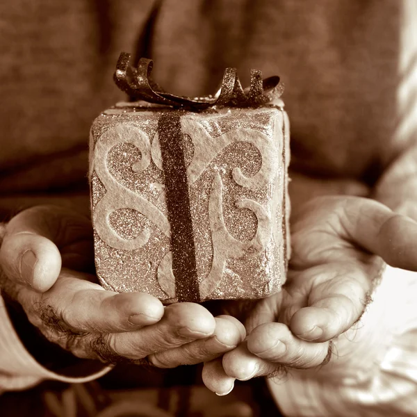Oude man met een geschenk, in sepia toning — Stockfoto