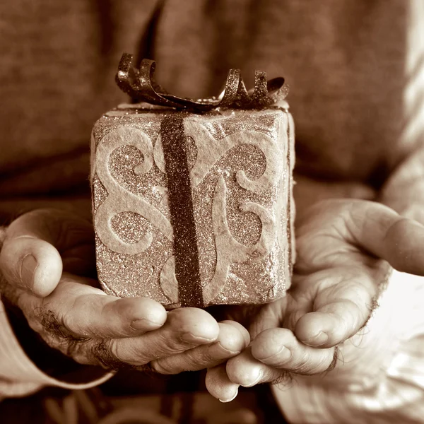 Velho com um presente, em sepia tonificação — Fotografia de Stock