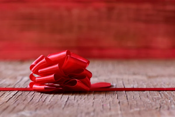 Lazo de cinta roja sobre una superficie de madera — Foto de Stock