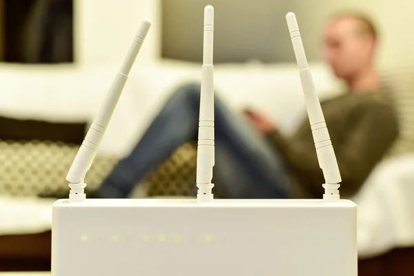 Router inalámbrico y hombre joven usando un teléfono inteligente —  Fotos de Stock