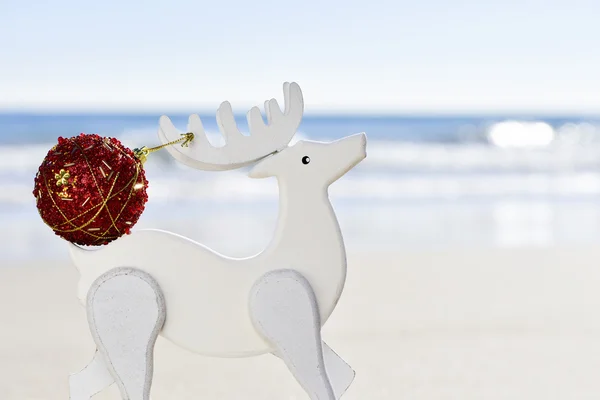 Palla di Natale nella corna di una renna di legno sulla spiaggia — Foto Stock