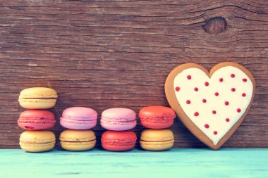 macarons and heart-shaped cookie on a blue rustic surface clipart