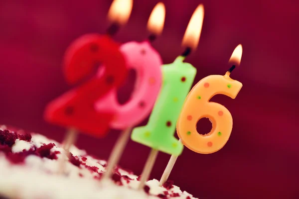 Aydınlatılmış sayı şeklindeki mumlar şekillendirme 2016 bir pasta üzerinde numara. — Stok fotoğraf