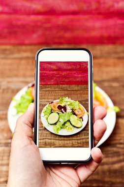 adam onun smartphone ile bir salata bir resim çekmek