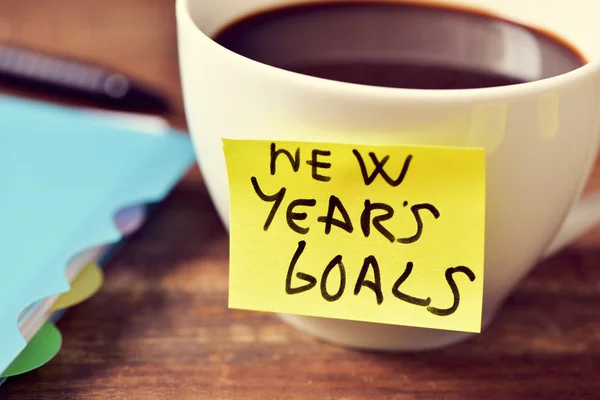 Coffee and a sticky note with the text new years goals — Stock Photo, Image