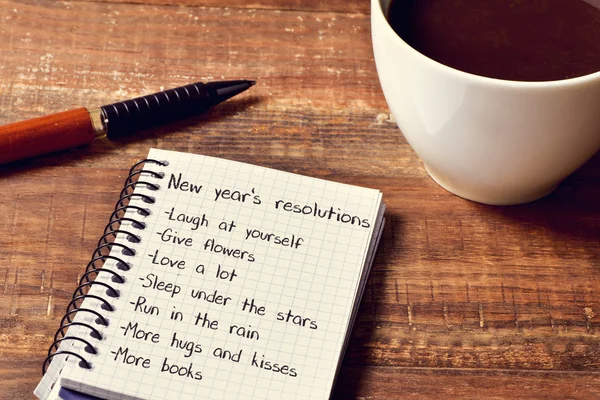 Кофе и блокнот со списком новогодних резолюций — стоковое фото