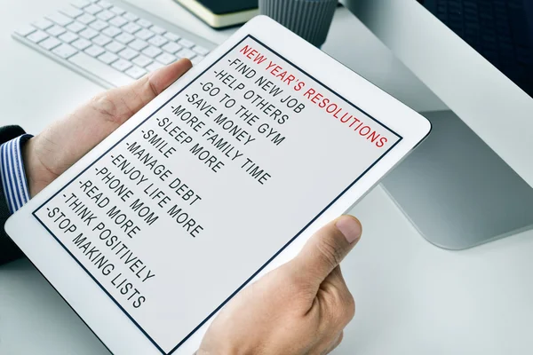 Homme avec une liste de résolutions de nouvelles années dans une tablette — Photo