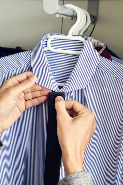 Jovem escolhendo um empate e uma camisa do armário — Fotografia de Stock