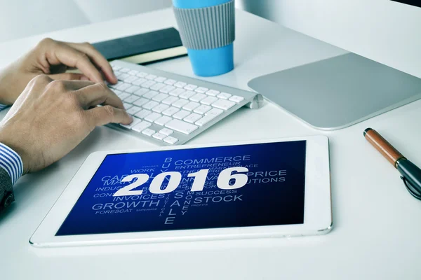 Businessman with a tag cloud of goals for the 2016 in his tablet — Stock Photo, Image