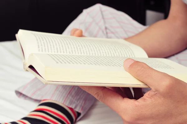 Young man reading a book in bed — Stock Photo, Image