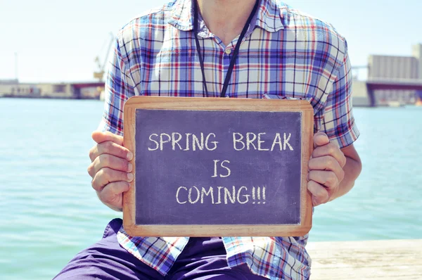 Young man with a chalkboard with the text spring break is coming — Stock Photo, Image