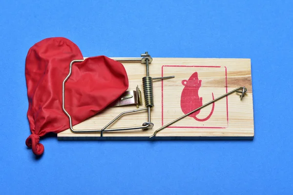 Deflated heart-shaped balloon in a mousetrap — Stock Photo, Image