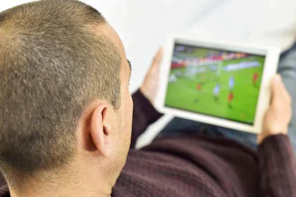Joven viendo un partido de fútbol en su tableta — Foto de Stock