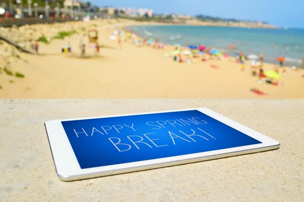 Tablet met de tekst happy voorjaarsvakantie op het strand — Stockfoto