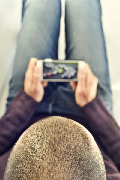 Jonge man kijken naar een autorace in zijn smartphone — Stockfoto