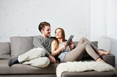 Romantik rahat genç çift kanepede tablet bilgisayar kullanarak