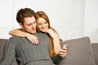 Cep telefonunda bir şey izlerken kanepede oturan Çift