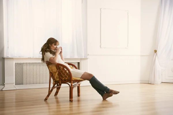 Pencere önünde oturan ve kahve veya çay içme genç kadın — Stok fotoğraf
