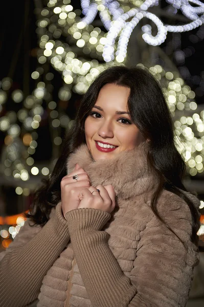 Hermosa mujer con luces de invierno detrás de la ciudad — Foto de Stock