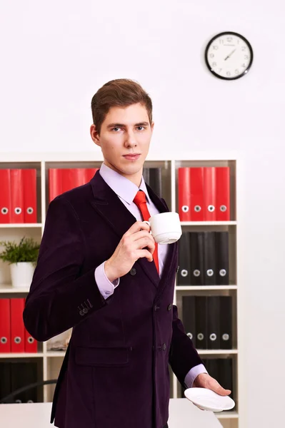 Junger Mann posiert mit Kaffeetasse im Büro — Stockfoto