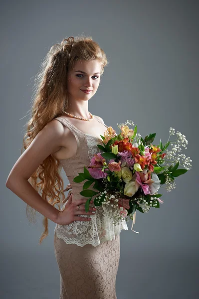 Pretty woman in dress with bouquet of flowers — Stock Photo, Image
