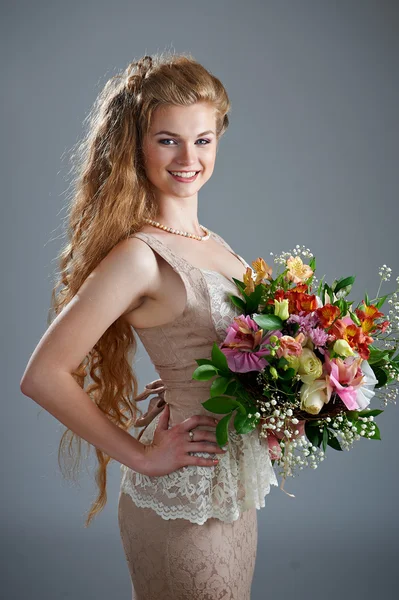 Pretty woman in dress with bouquet of flowers — Stock Photo, Image