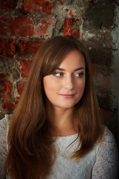 Pretty young girl against a brick wall — Stock Photo, Image