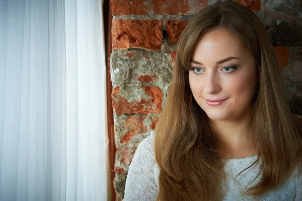 Pretty young girl against a brick wall — Stock Photo, Image