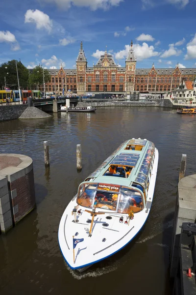 canal cruise boat in front of amsterdam central railway station