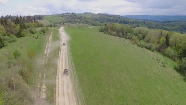 SUV konvooi reis door de bergen van de Karpaten. de Camera-vliegen boven de bomen en de velden Over rotsen en weiden — Stockvideo